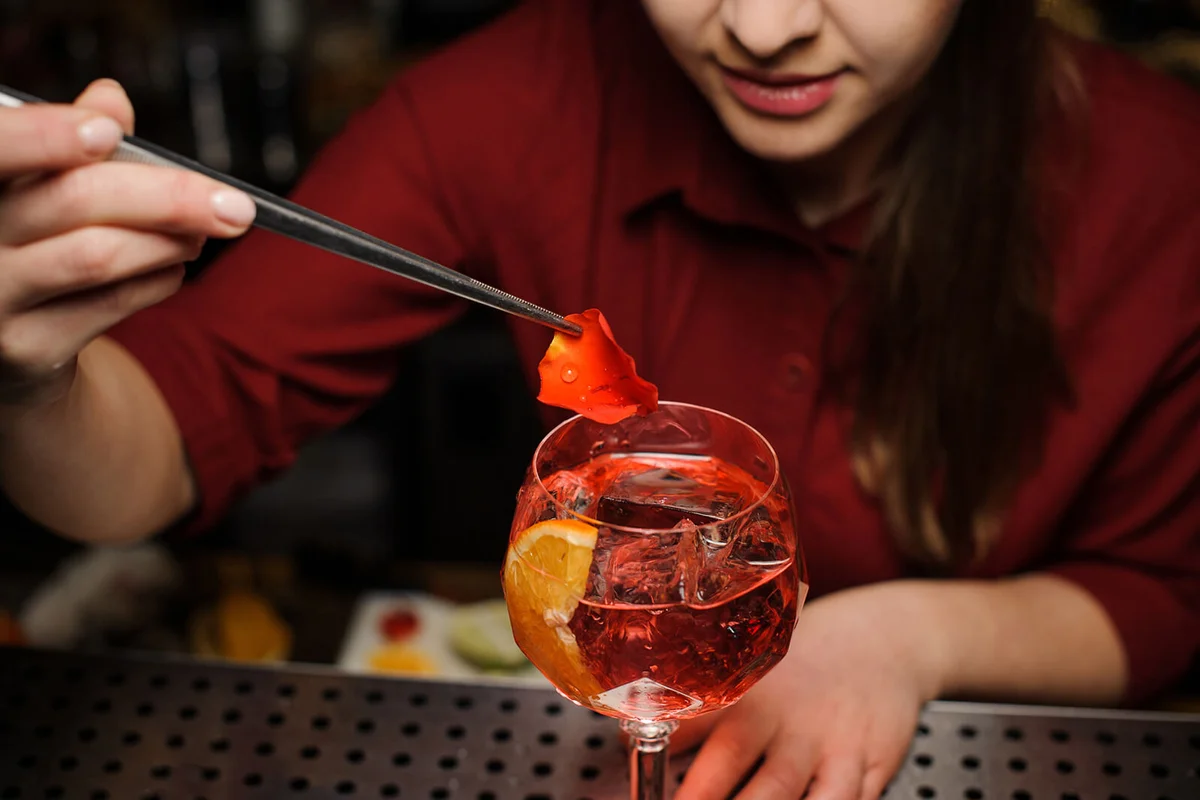barman decorating a glass of Aperol syringe cocktail