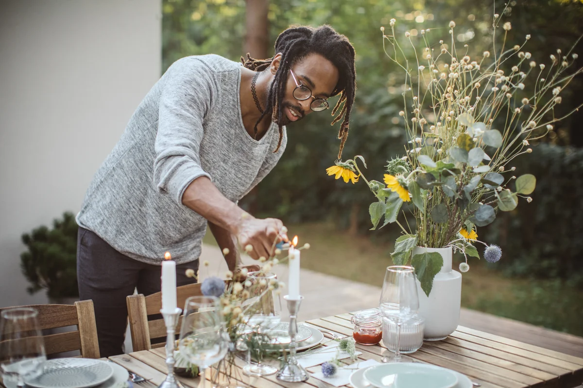 Man lighting candles at dining table