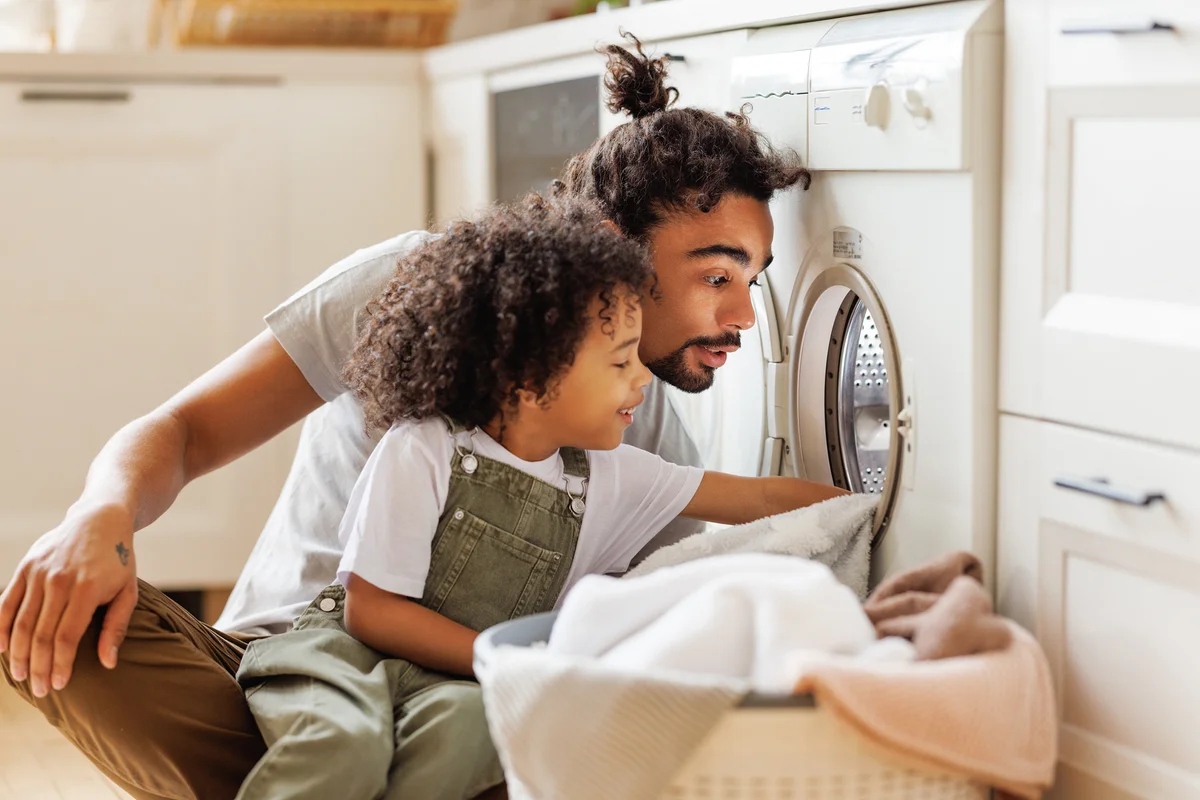 kid doing laundry with dad