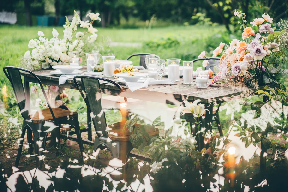 Rustic wooden table with elegant festive setting decorated with fresh pastel aromatic flowers