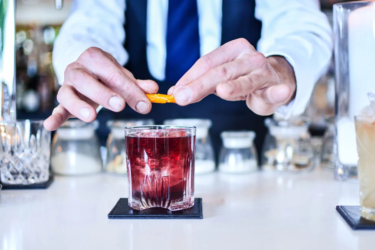 Bartender garnishing a beet negroni