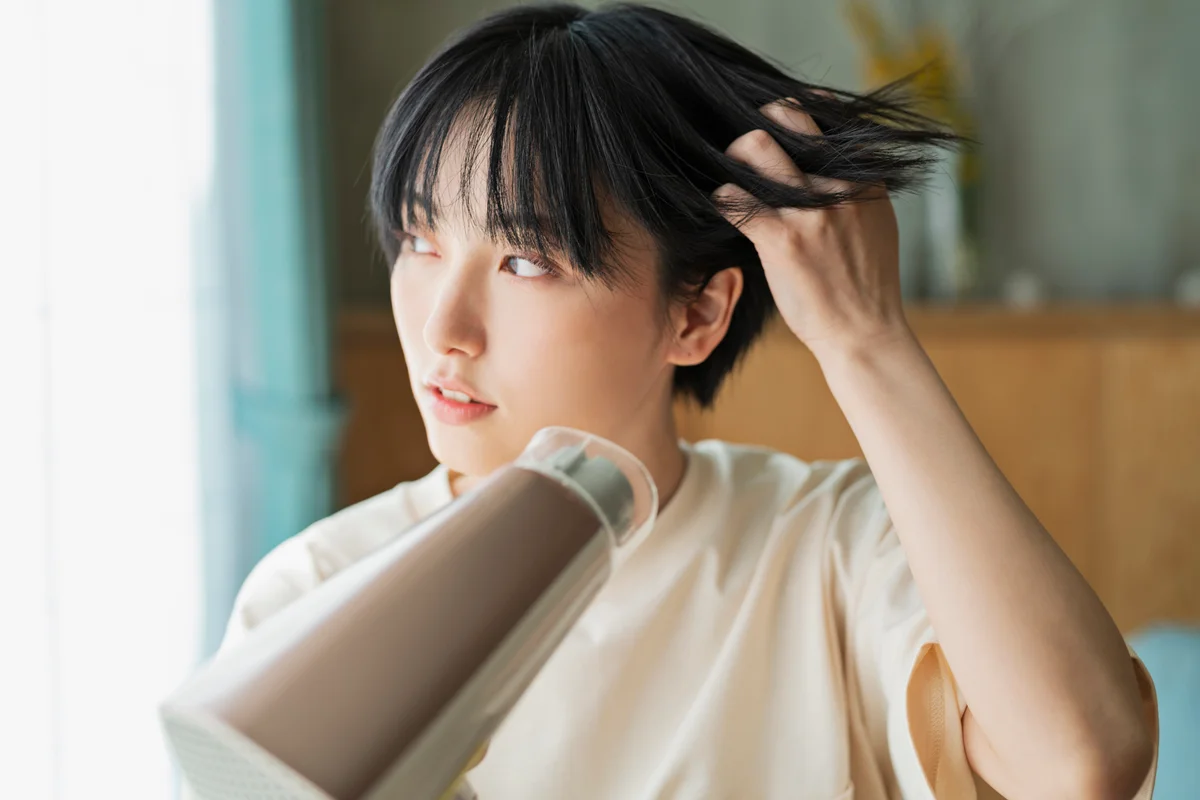 woman blow drying her short black hair