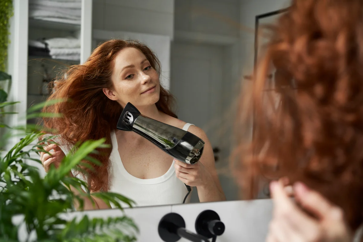 woman blow drying her red hair