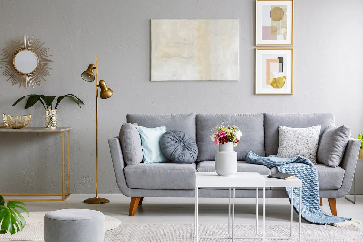 Gold mirror above shelf with plant in grey living room