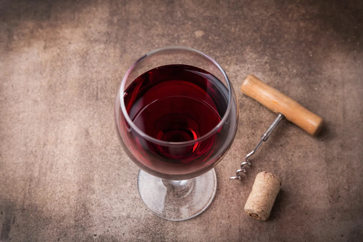 Glass of red wine and bottle on dark background
