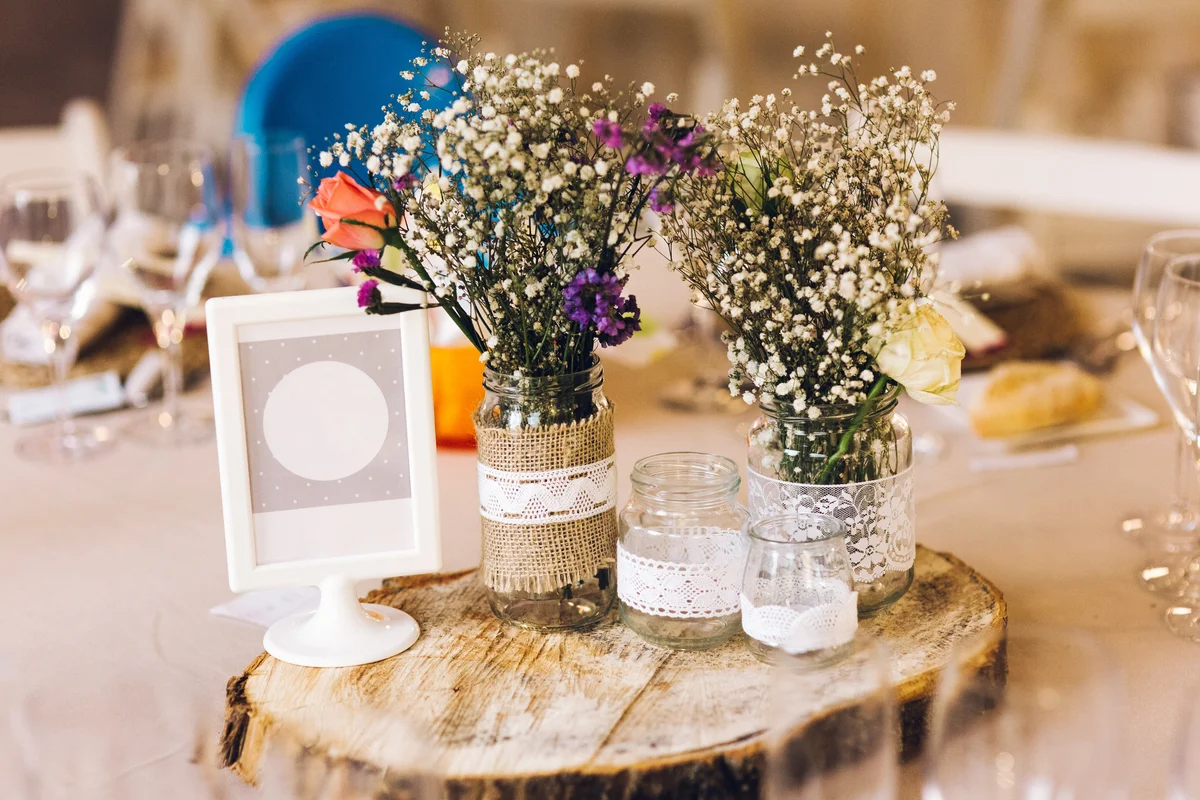 rustic centerpiece made of flowers in jars on a slab of wood
