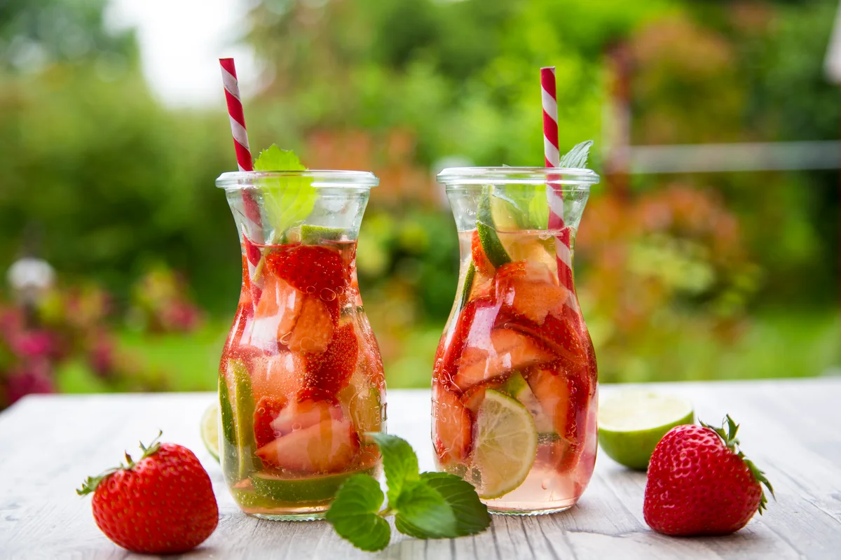 Two glass bottles with a drink infused with strawberries and lime