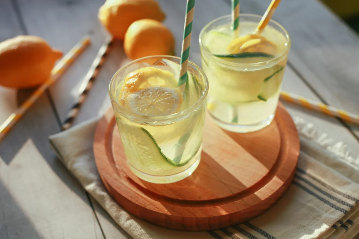 Glass of homemade lemonade made of lemon and cucumber with paper drinking straws.