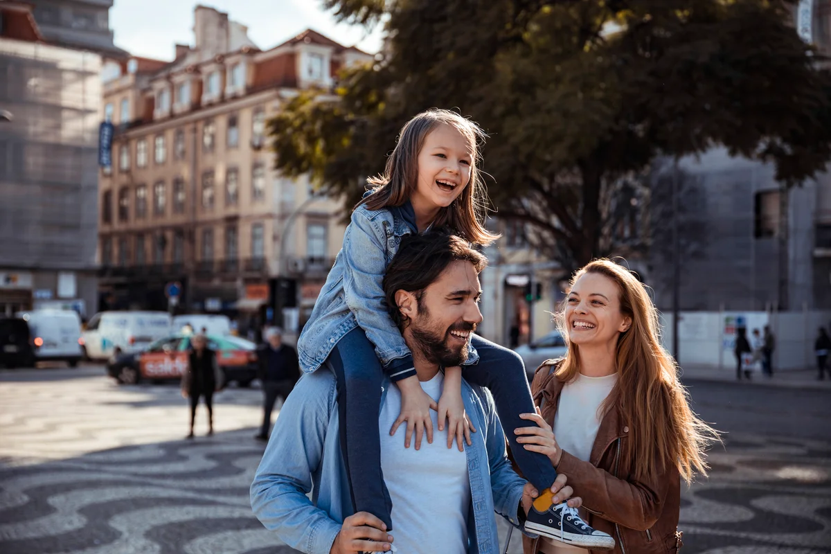 father with daughter on shoulders smiling with mom beside them