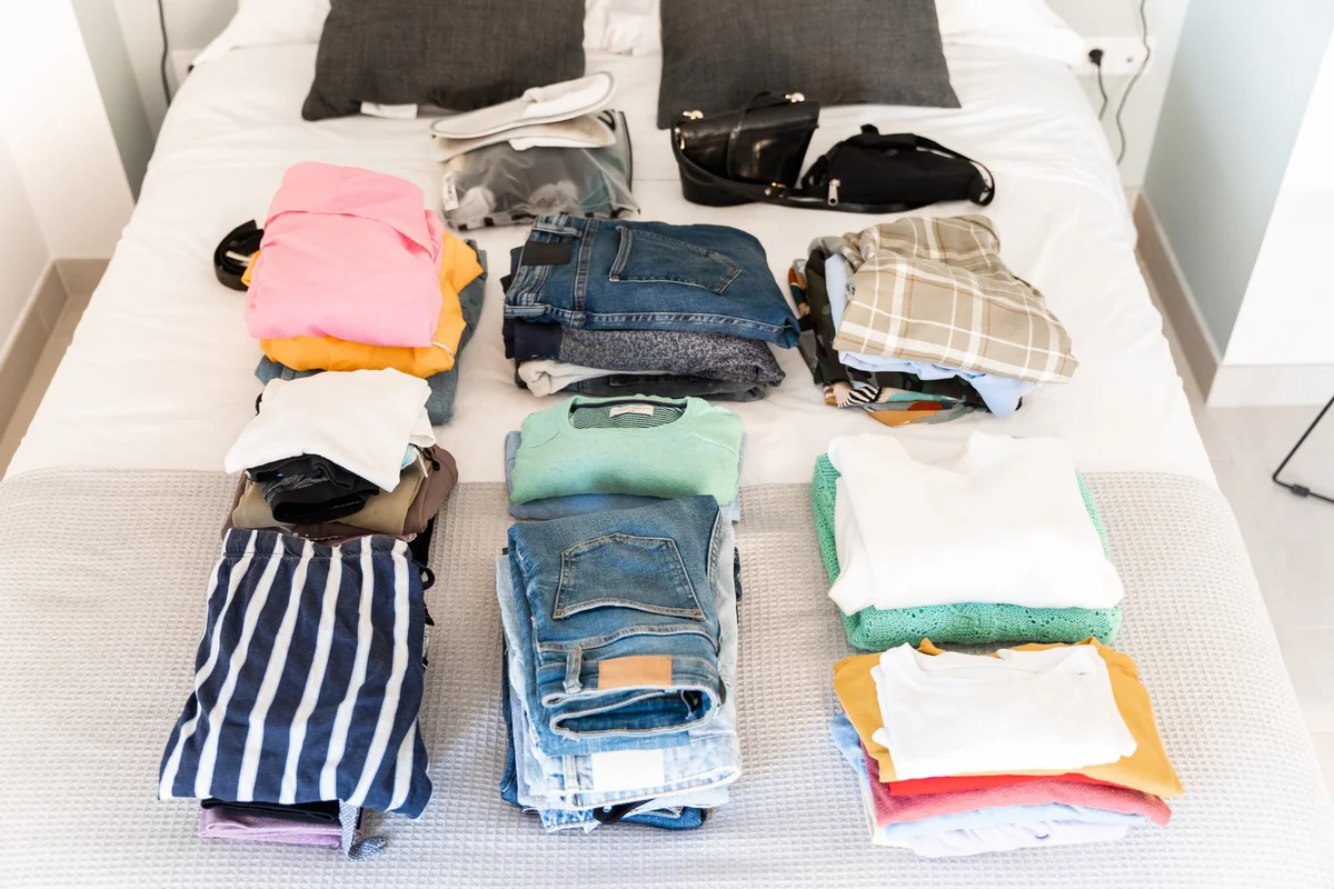 clothes sorted into piles on bed