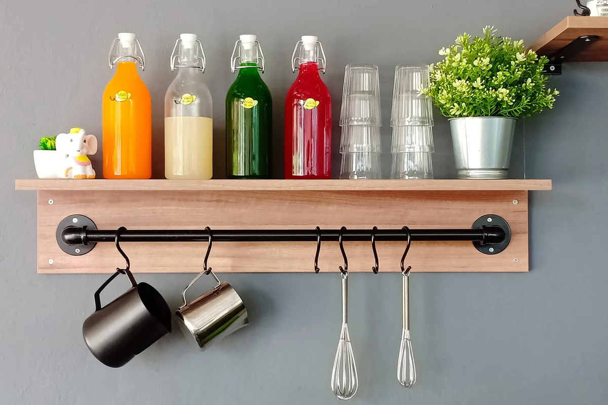 Colorful Bottles With Glass And Flowers On Shelf At Home