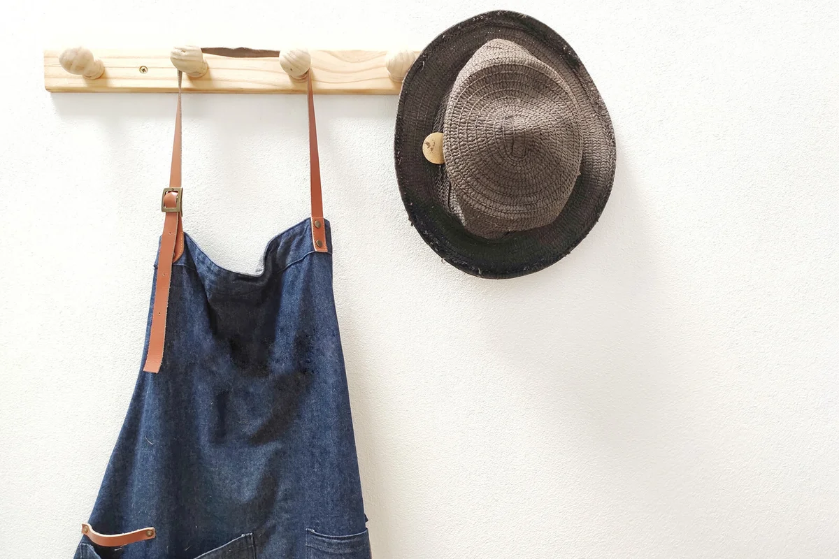 Apron And Hat Hanging Against White Wall