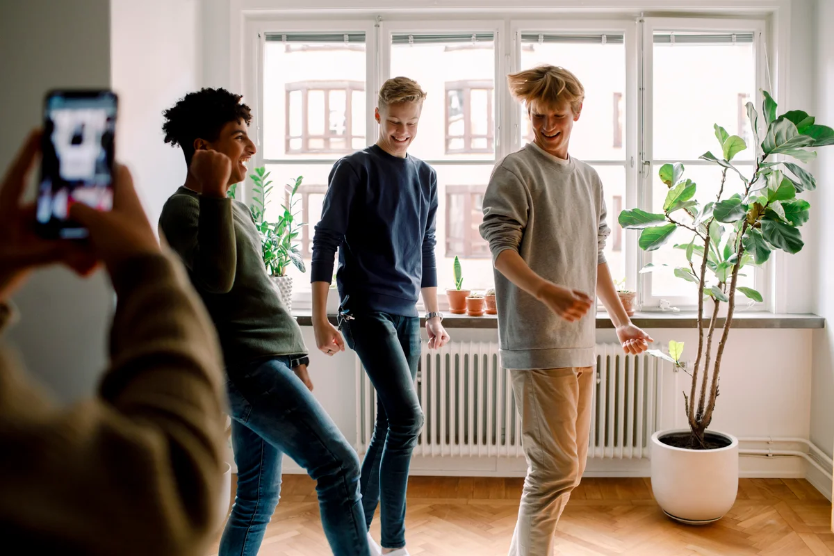 girl filming 3 boys learning a dance