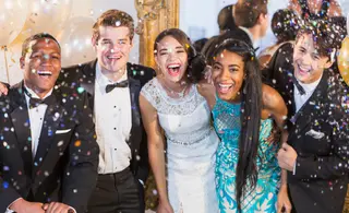 group of teens at prom smiling at camera with confetti falling around them