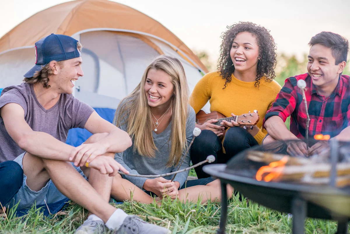 Group of friends sitting around campfire and camping out