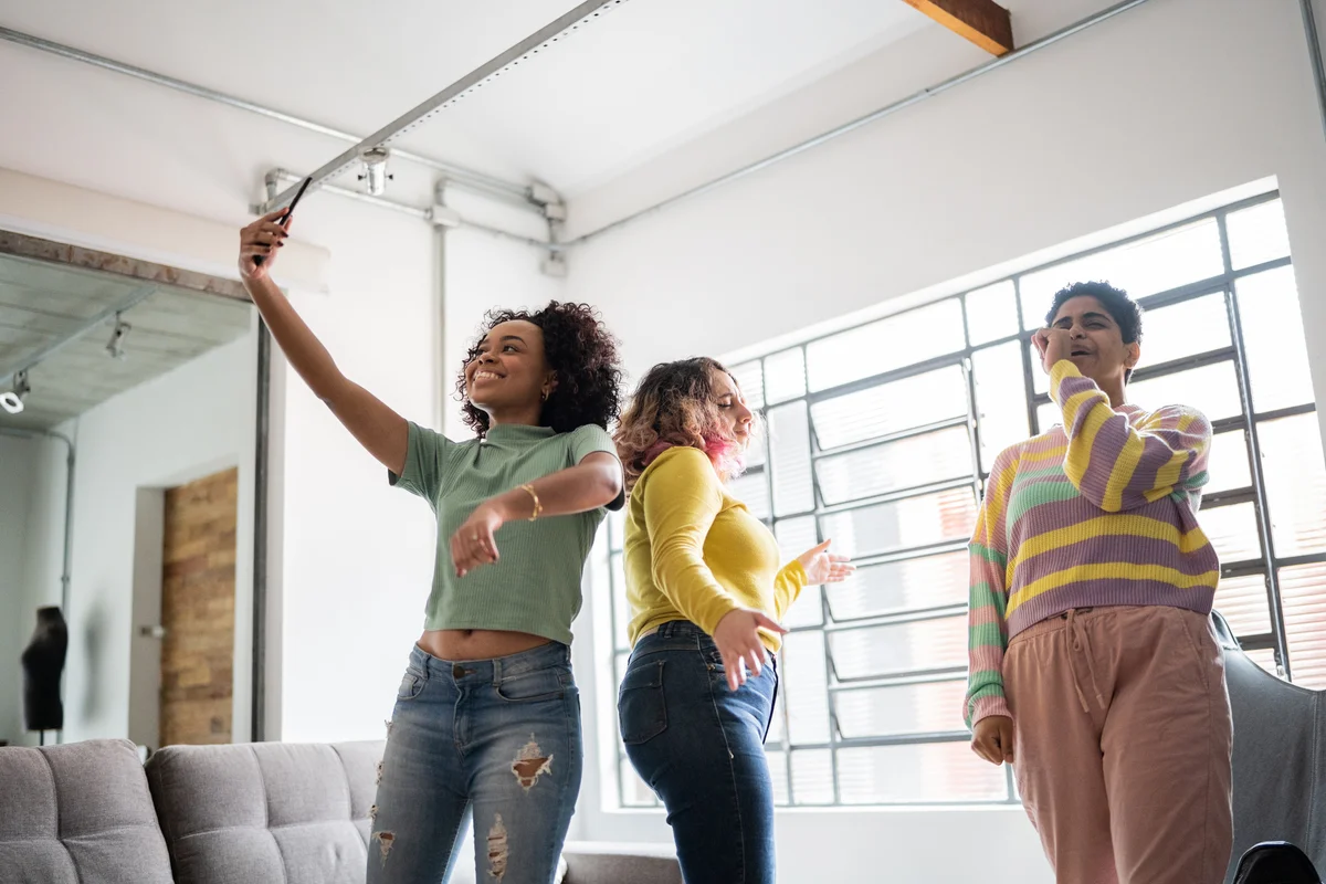 three friends singing and dancing in living room