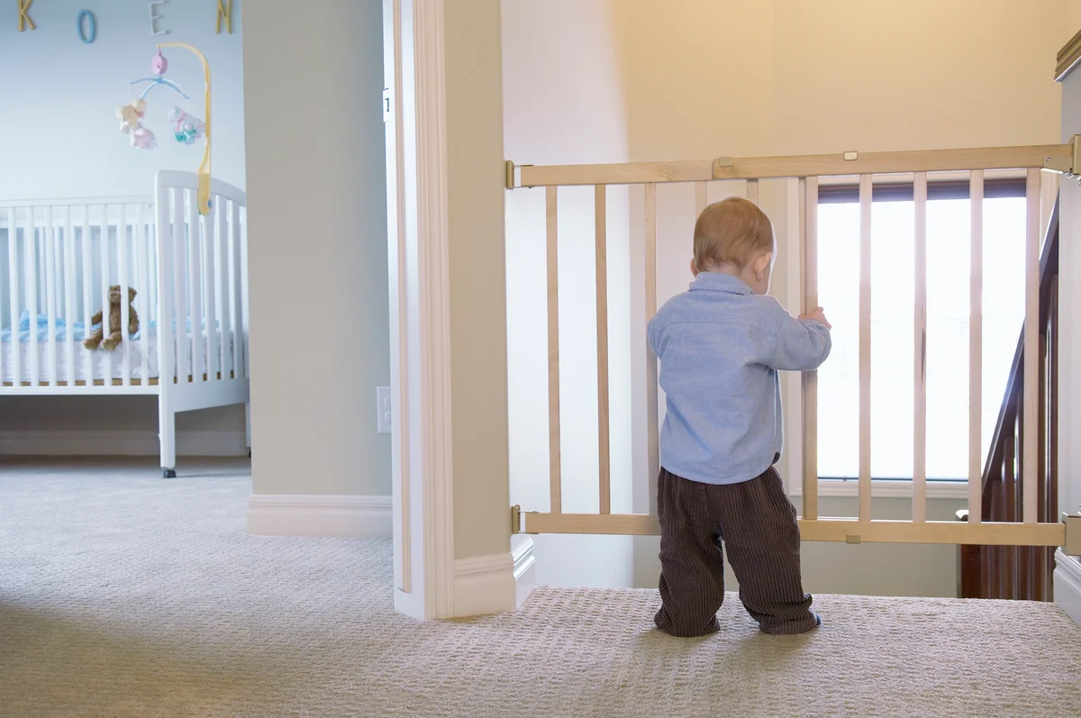 baby looking out baby gate next to his bedroom