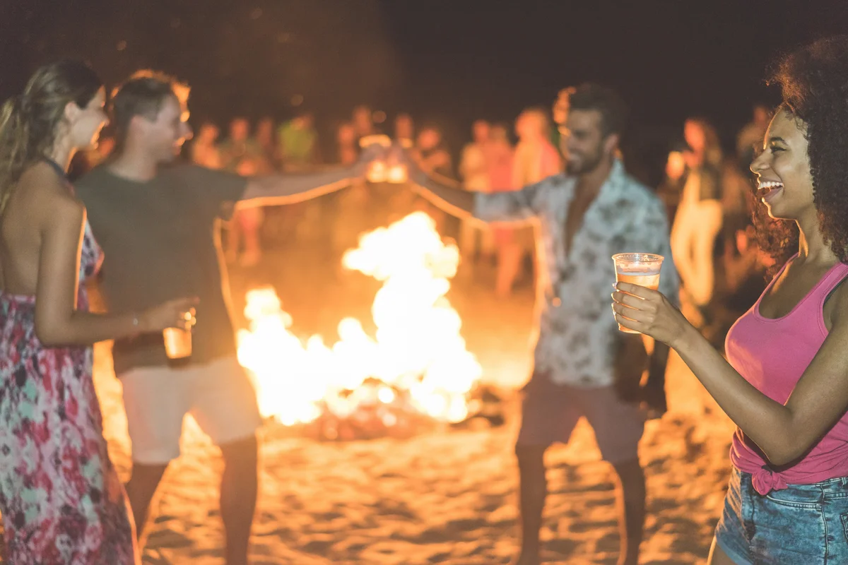 people partying outside around a beach bonfire