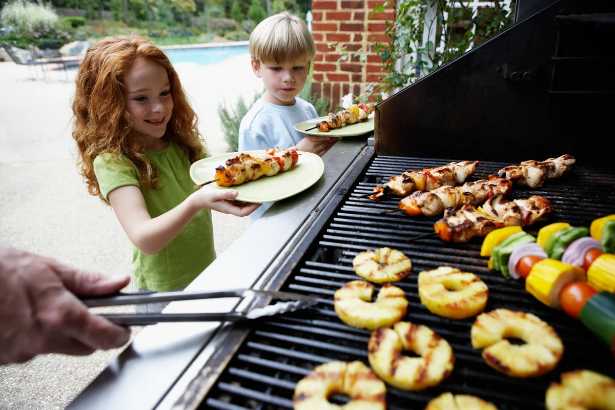 Kids getting kabobs off of grill