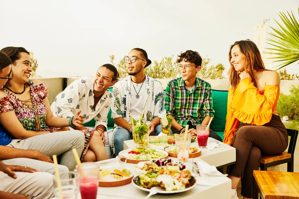 friends laughing together during meal in tropical setting