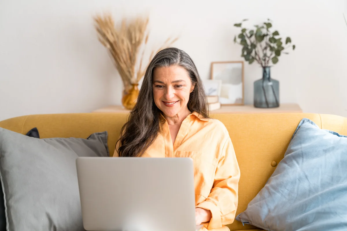 older woman sitting on couch on her laptop