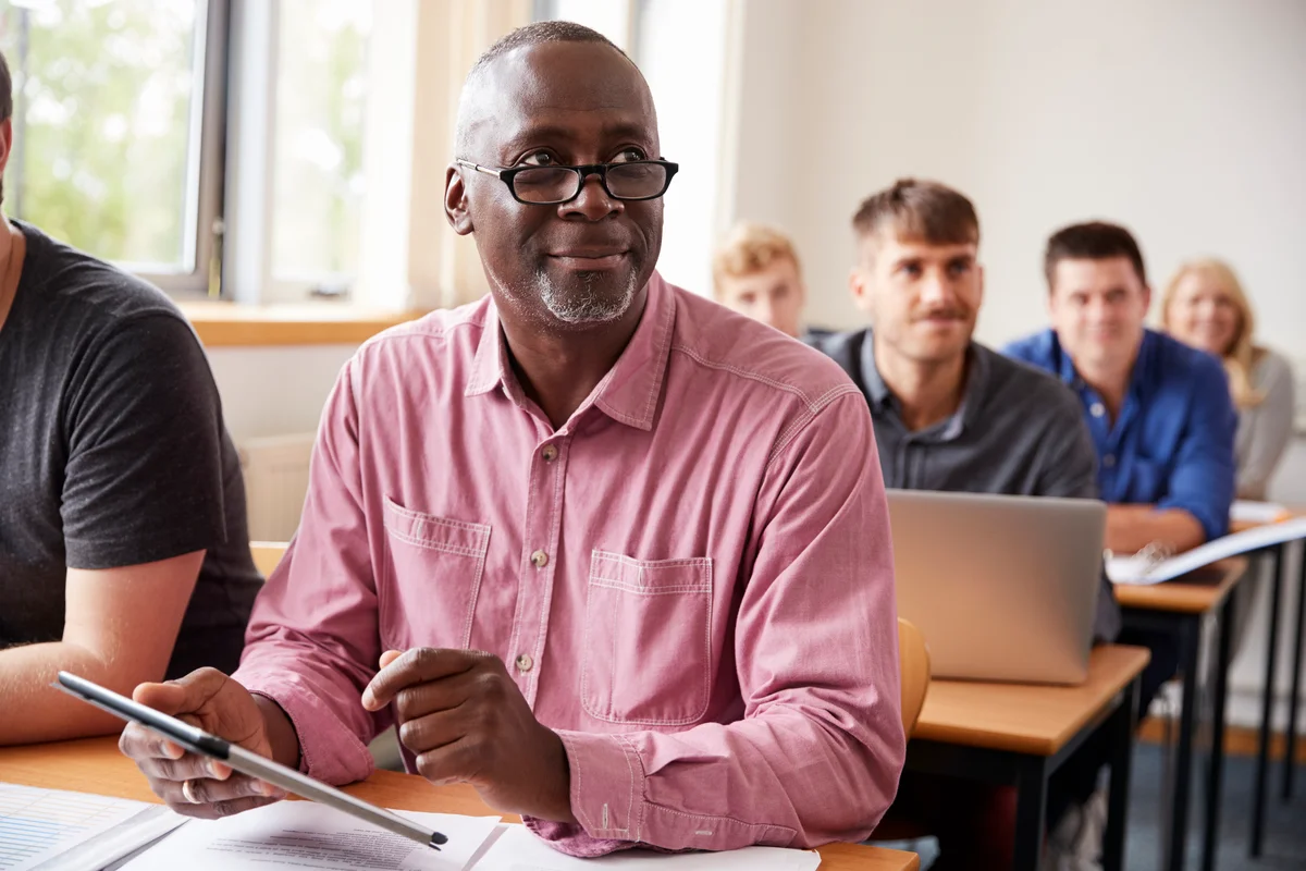 older man learning in a classroom