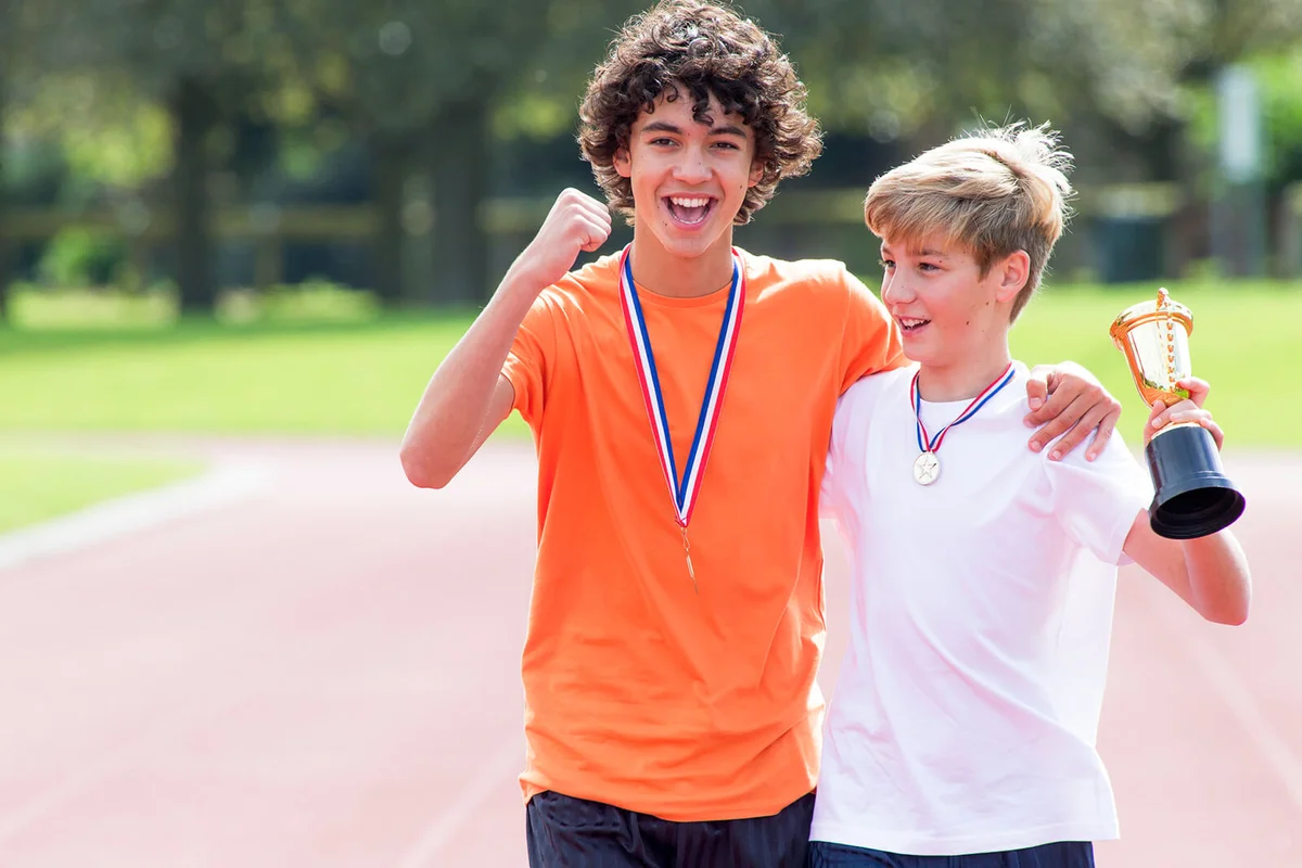 Two young teenage boys standing on running track