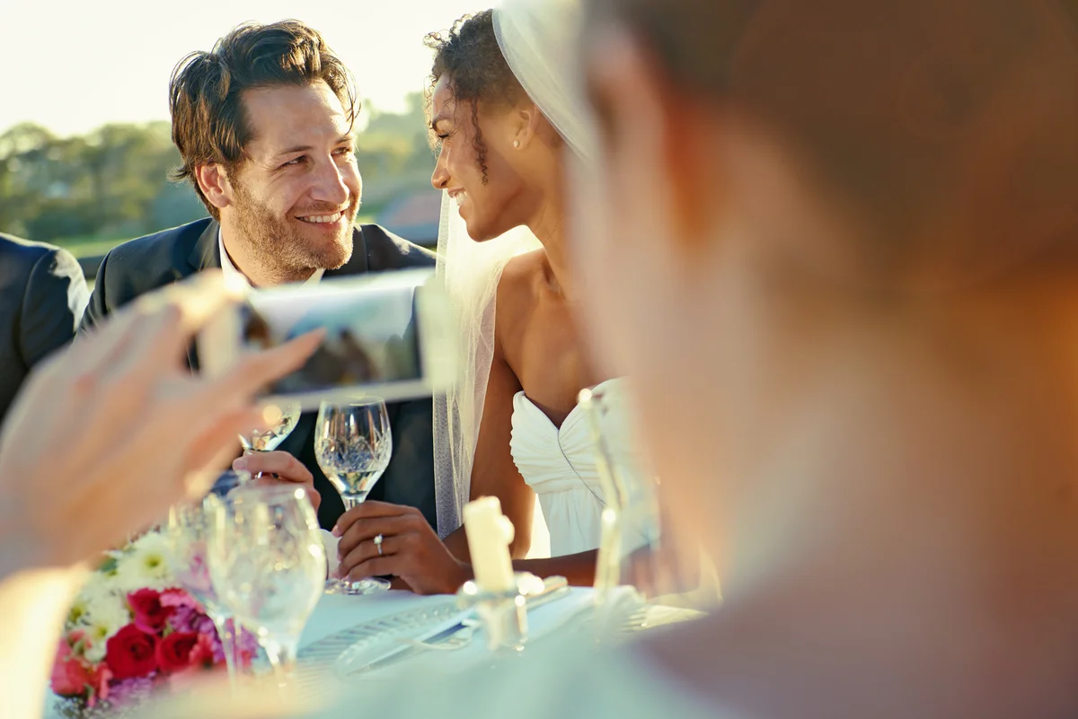 man taking photo of bride and groom on his phone