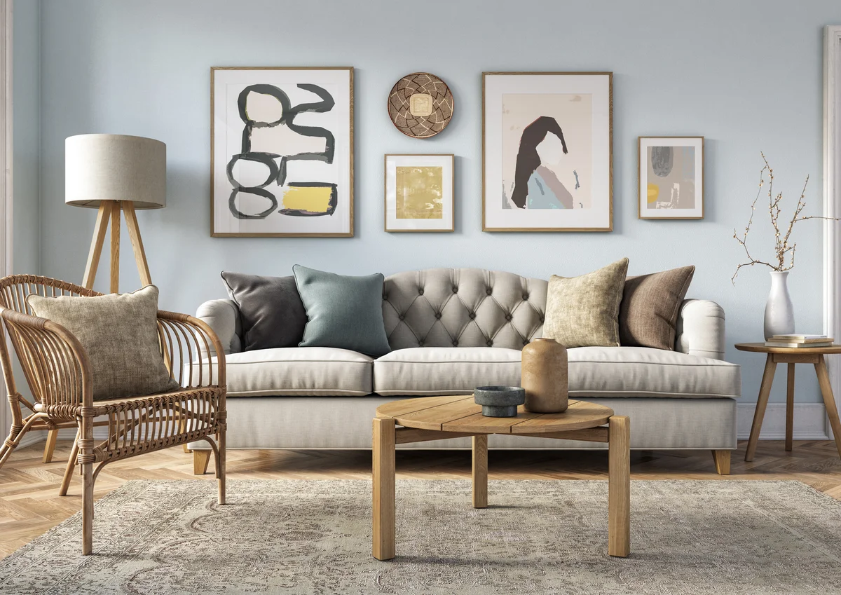 Bohemian living room interior with beige colored furniture and wooden elements and light blue colored wall