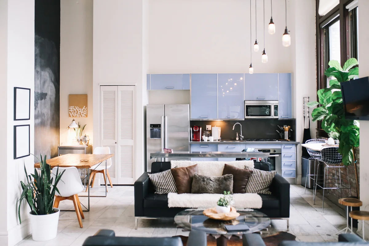 Interior of a large and bright loft apartment in Downtown Los Angeles, California. Living room with sofa and a worktable, with kitchen in the back.