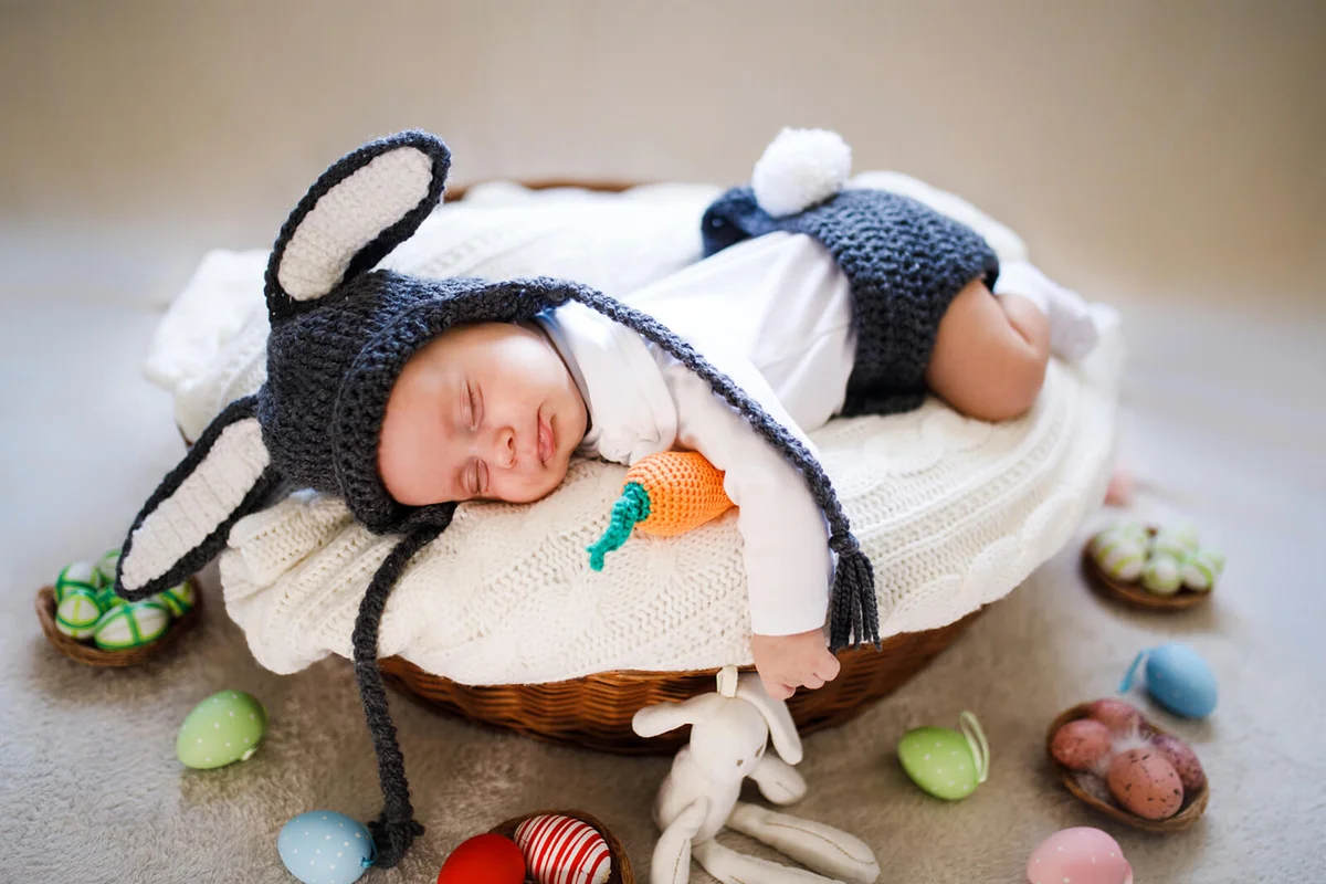Newborn baby boy wearing bunny ears and tail in a basket