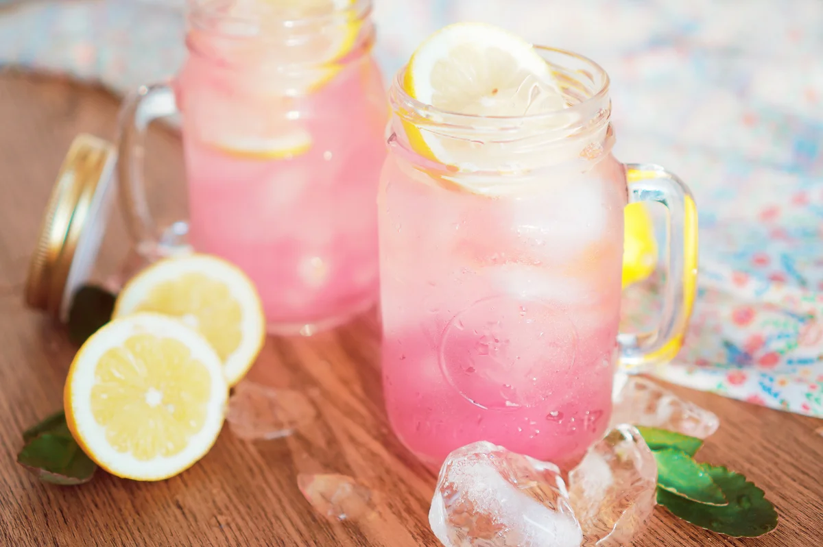 Pink lemonade in mason jars on wooden surface