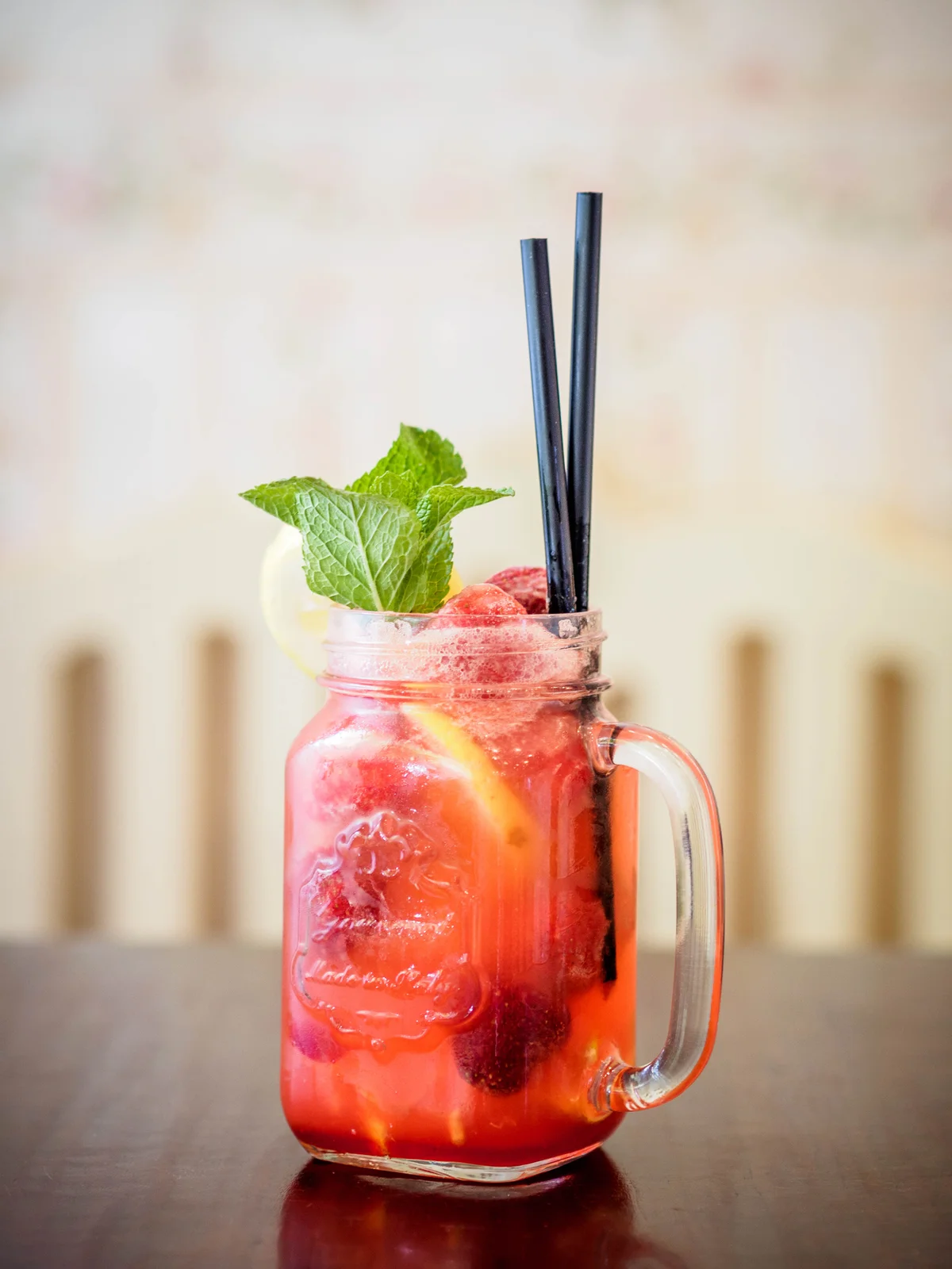 Pink colored lemonade in mason jar with berries and mint for garnish