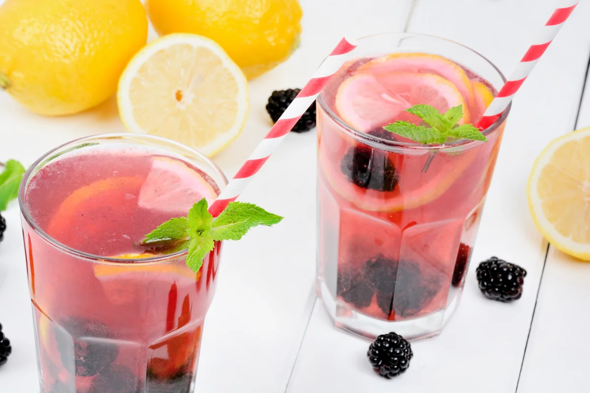 Blackberries lemonade in a glasses on a white wooden table