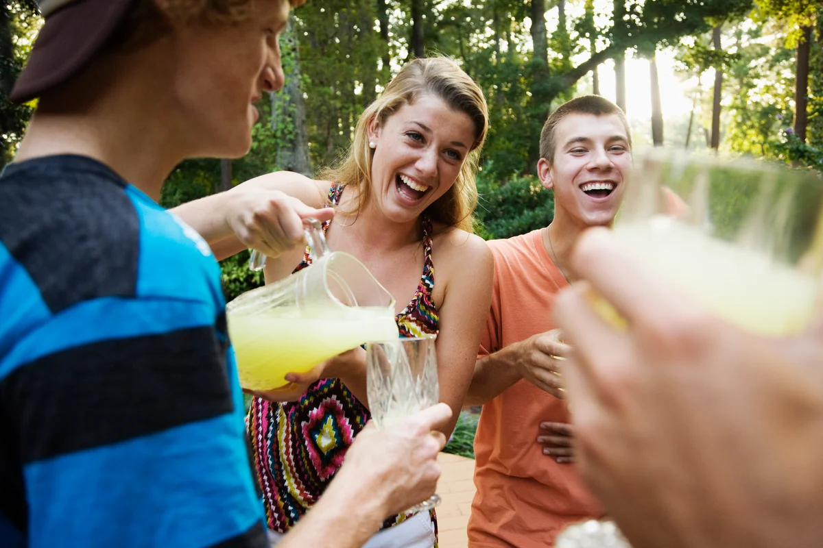 Woman pouring lemonade out of pitcher to group of friends