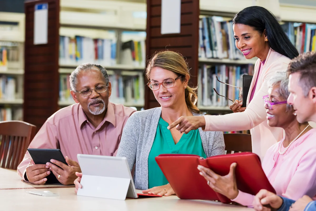 Elderly couple learning how to use devices with librarian