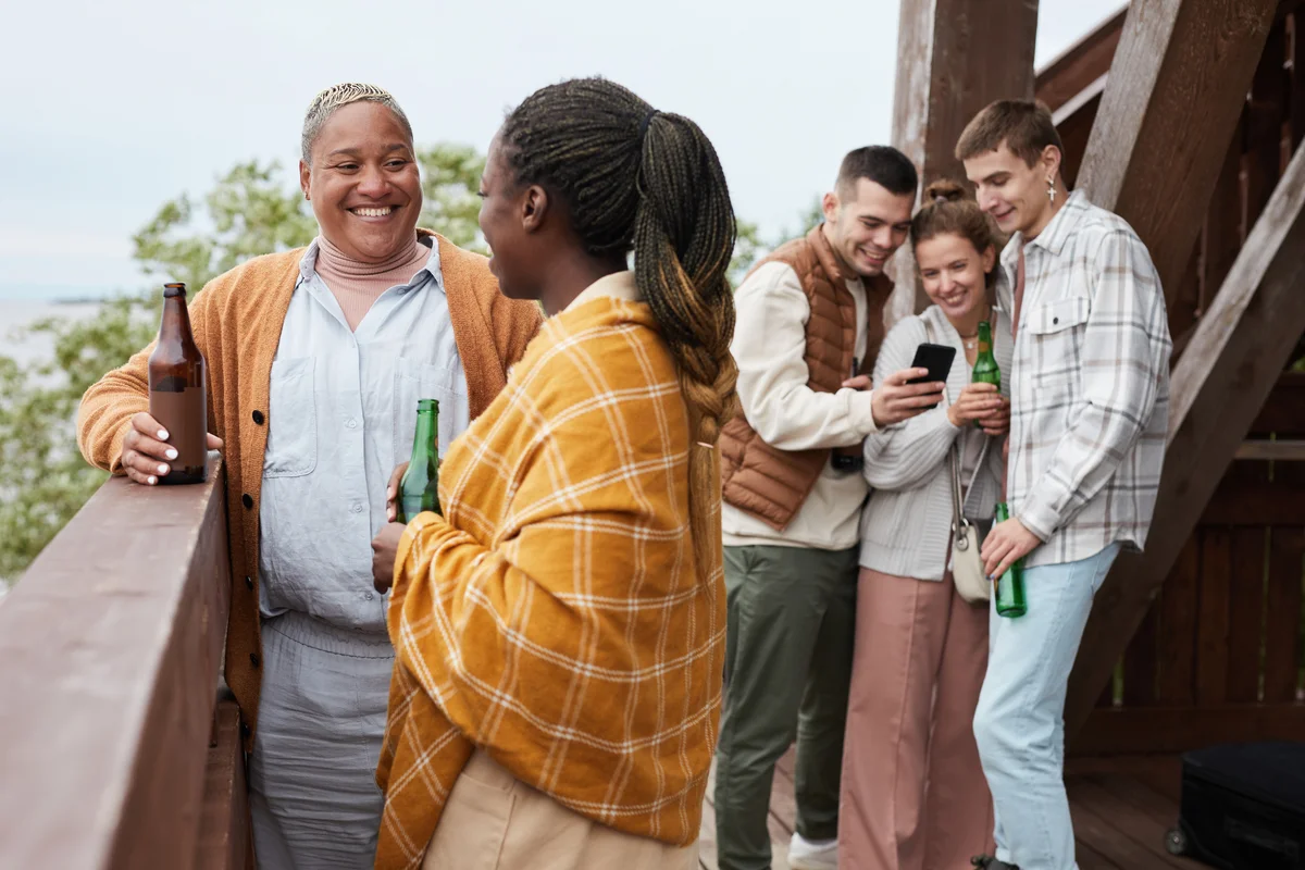 Friends enjoying beverages together on balcony by lake