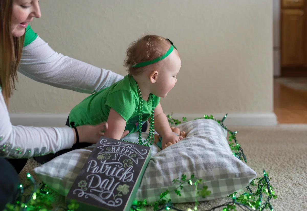 Mother posing baby on pillow with St. Patrick's Day decorations