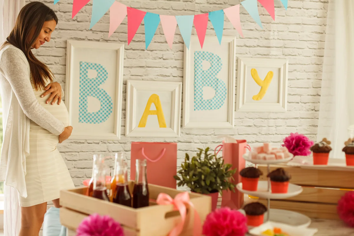 Pregnant woman posing by baby shower decorations