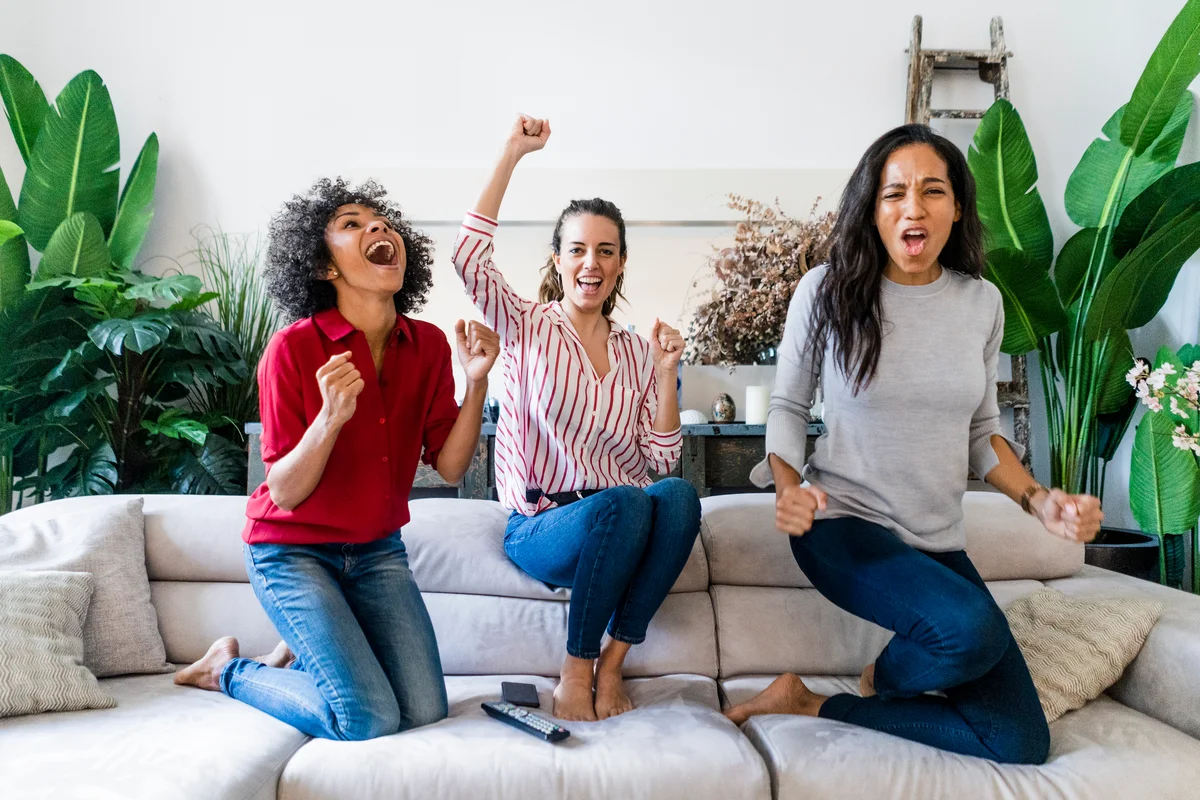 three women cheering while watching tv