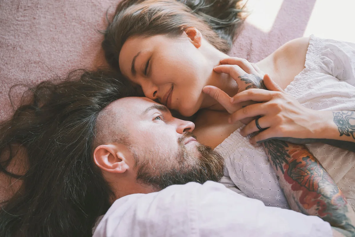 Romantic hipster couple lying on bed at home