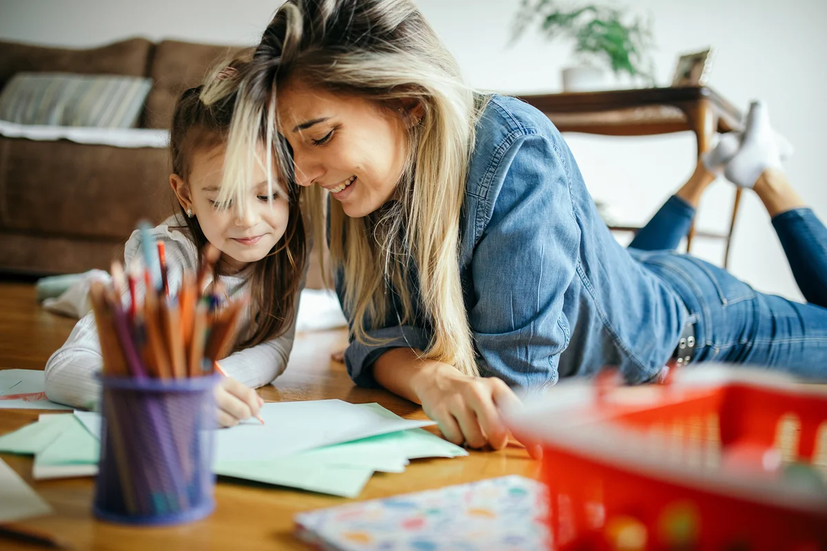 Woman spending some great time with little girl at home and they are drawing together