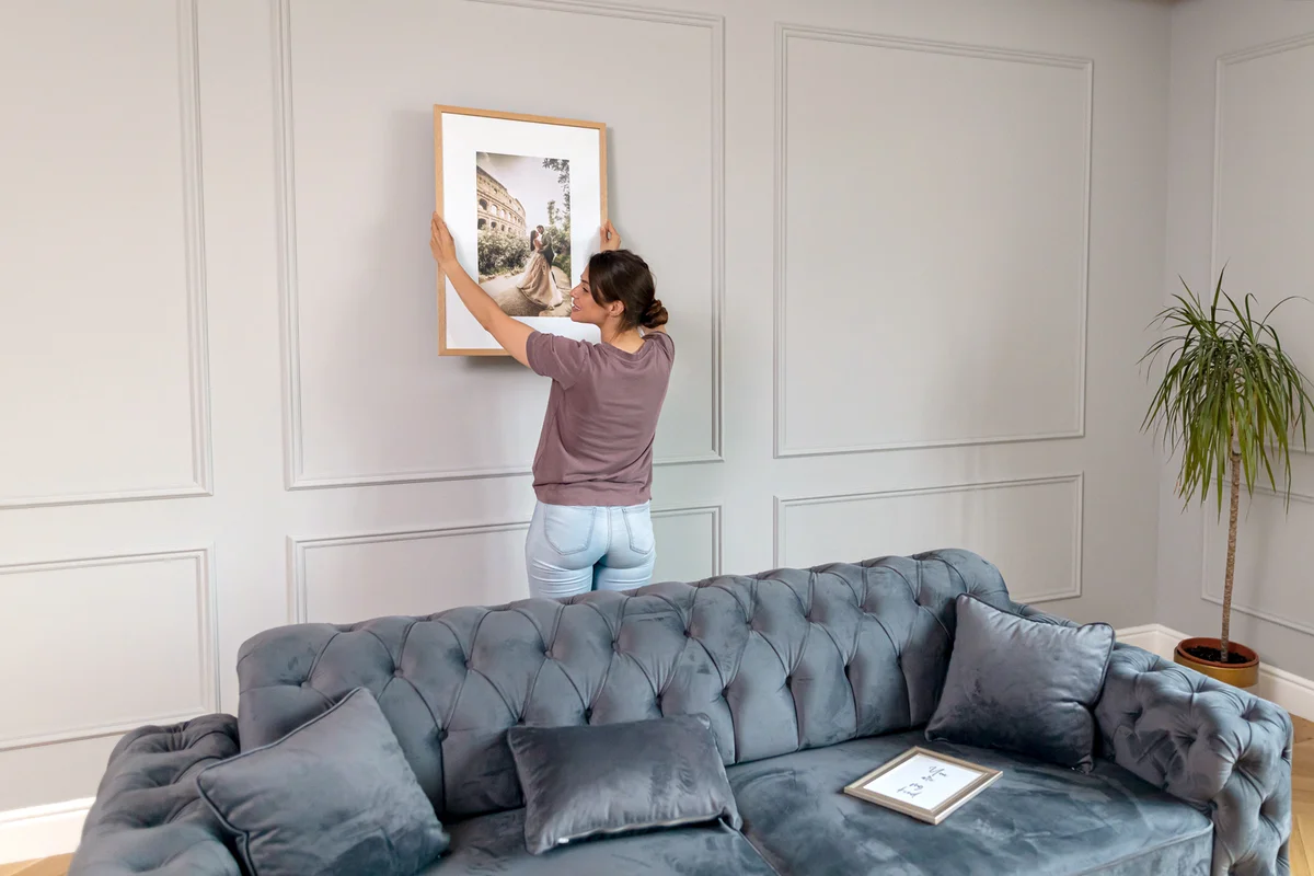 Woman hanging picture on the wall at home