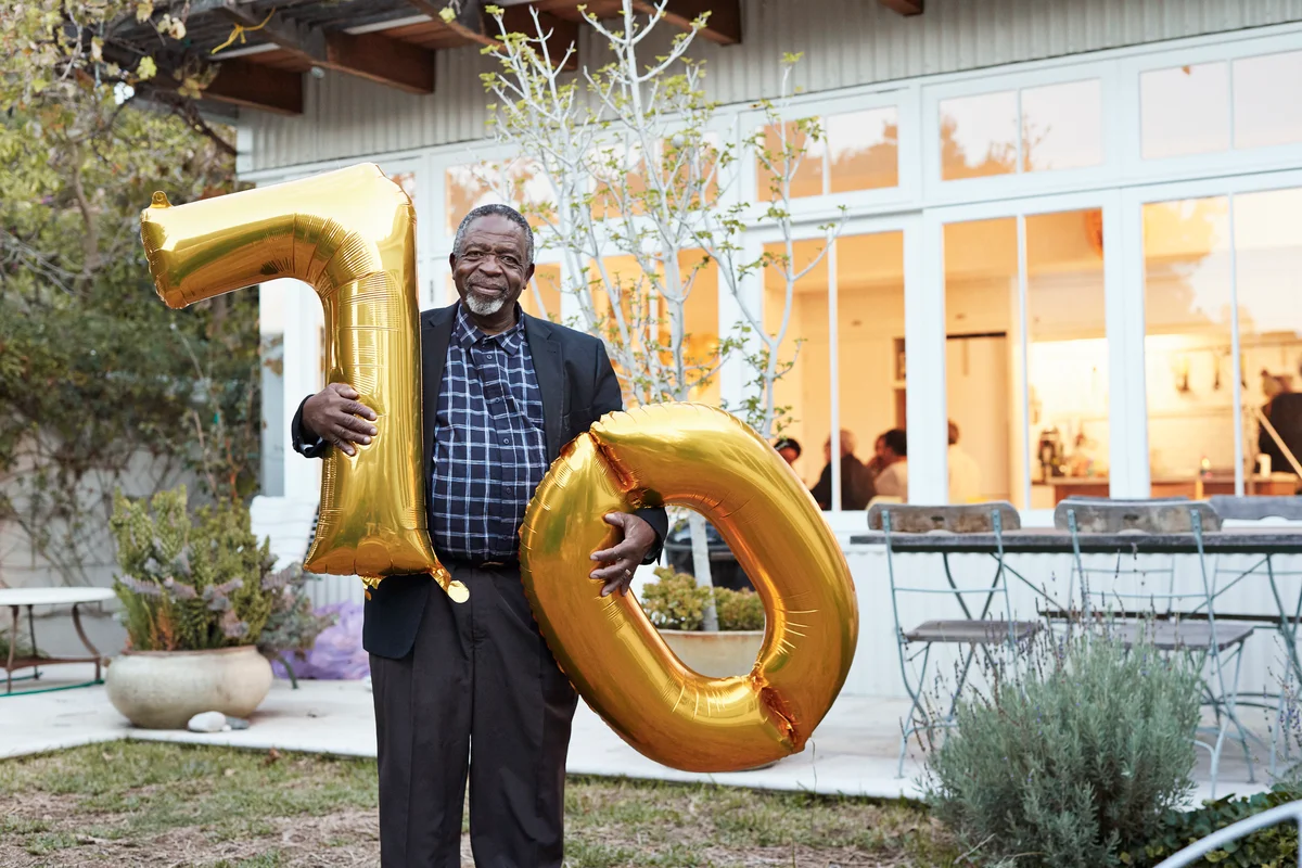 Man holding 70th birthday balloons