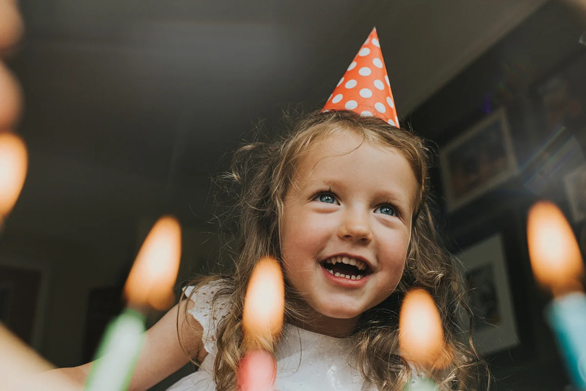 Cute little Girl above a Birthday cake, about to blow out the candles