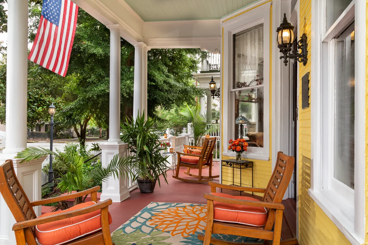 Traditional home front porch with chairs, outdoor rug and American flag