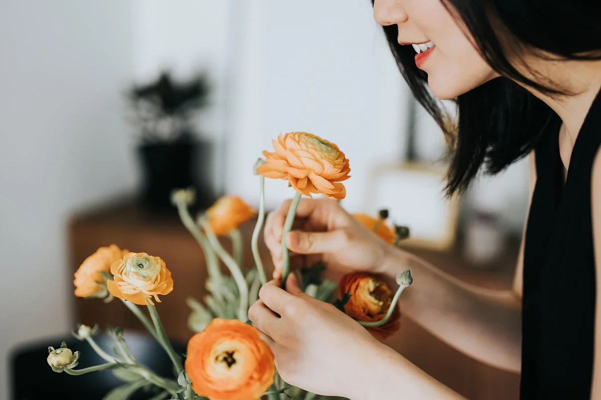 Woman smelling flowers while arranging it at home