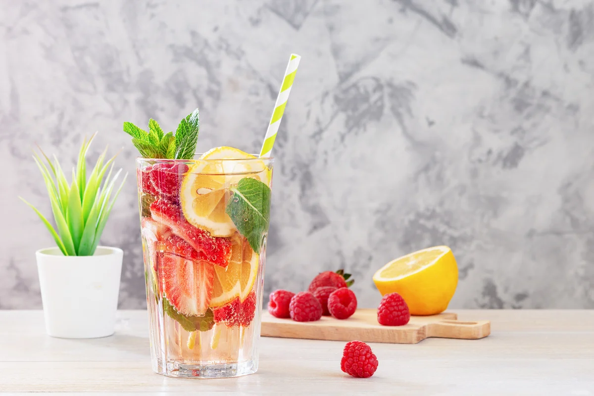 Drink glass with clear beverage and filled with lemons and strawberries