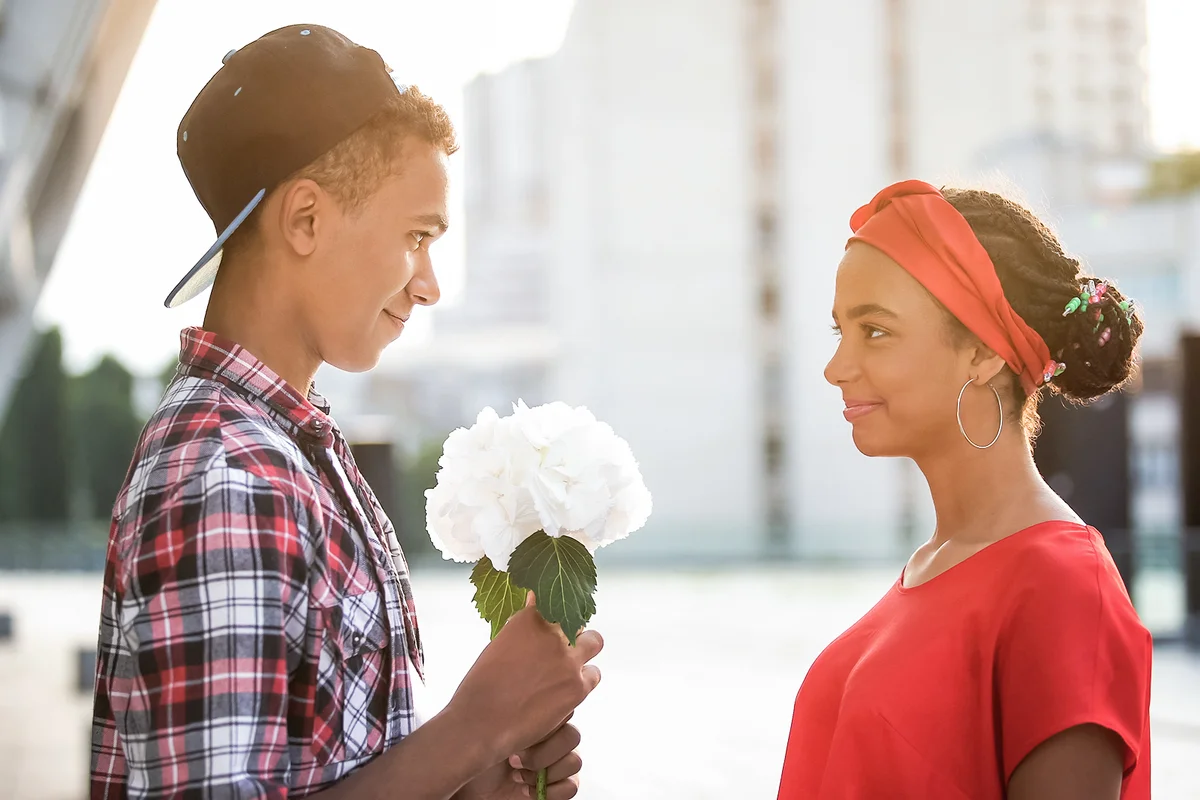 Teen boy giving flowers to beautiful girl