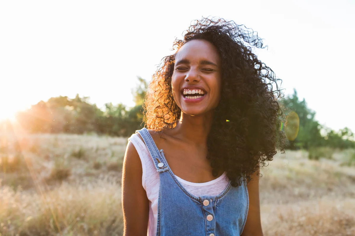 Girl smiling outside with sun behind her